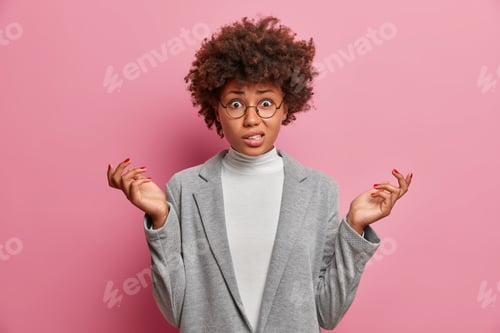Preview: Photo Of Puzzled Young African American Woman Entrepreneur With Curly Hair Raises Hands Shrugs