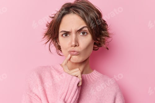 Vista previa: Serious Skeptical Woman Keeps Index Finger Near Folded Lips Raises Eyebrows Suspiciously Has Doubts