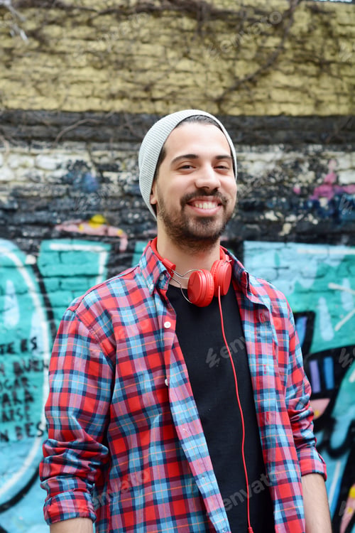 Preview: Portrait Of A Young Latin Man With Red Headphones Against Colorful Wall. Outdoors. Urban Concept.