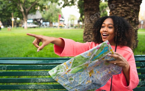 Preview: Portrait Of Young Beautiful Afro American Woman Holding A Map And Pointing Somewhere. Travel