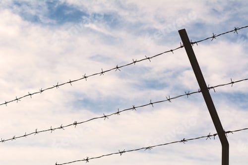 Preview: Fence Of Barbed Wire Against Blue Sky With Clouds.