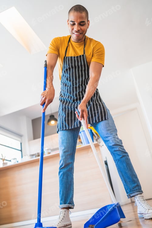 Preview: Portrait Of Young Latin Man Sweeping Wooden Floor With Broom At Home. Cleaning, Housework And