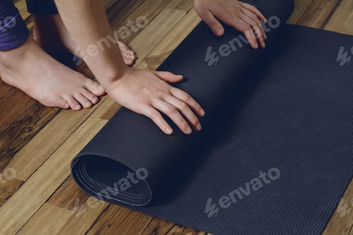 Preview: Close-Up Of Attractive Young Woman Rolling Her Fitness Mat Before Or After Yoga Class At Home