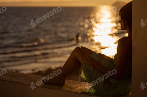 Preview: Silhouette Of A Young Woman Relaxing At The Beach And Enjoying The View Of A Beautiful Sunset