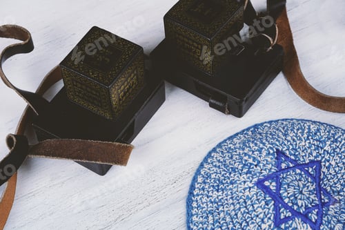Preview: Pair Of Tefilim With Black Straps With Blue Kippah On White Wooden Background. Jewish Lifestyle