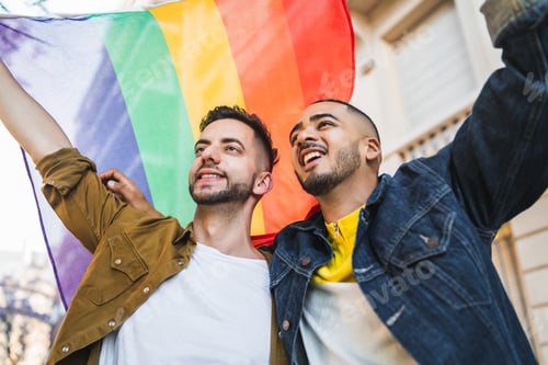 Preview: Portrait Of Young Gay Couple Embracing And Showing Their Love With Rainbow Flag At The Street. Lgbt