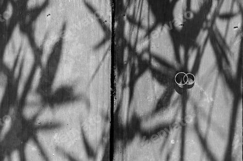 Preview: A Greyscale High Angle Shot Of Two Wedding Rings Put On Each Other On A Wooden Surface With Shadows