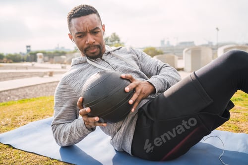 Preview: Portrait Of An Athletic Man Doing Abdominal Exercise With Medicine Ball In The Park Outdoors. Sport