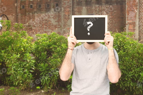 Preview: Portrait Of Handsome Young Man Holding Chalkboard With Question Mark. Outdoors.