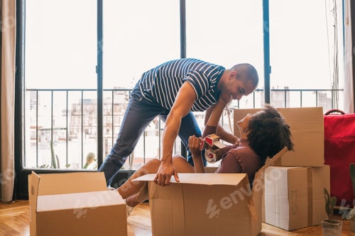 Preview: Portrait Of Happy Latin Couple Having Fun With Cardboard Boxes In New House At Moving Day. Real