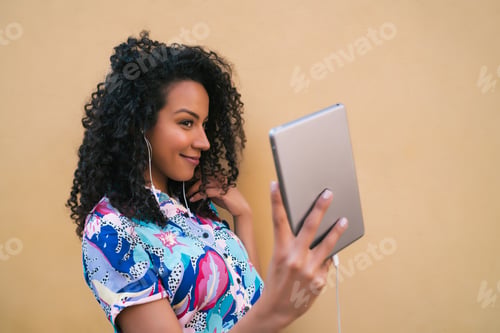 Preview: Portrait Of Afro Woman Taking Selfies With Her Digital Tablet Against Yellow Wall. Technology