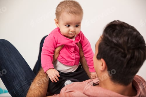 Visualização: Jovem pai relaxando com sua filha em casa e olhando um para o outro
