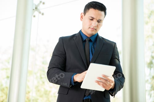 Preview: Young Hispanic Man In A Suit Using A Laptop Computer To Check His Emails