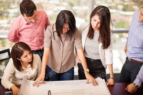 Preview: High Angle View Of A Group Of Architects Looking At A Building Plan In A Meeting Room