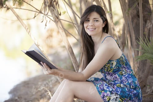 Preview: Cute Latin Woman Reading A Book While Relaxing Outdoors