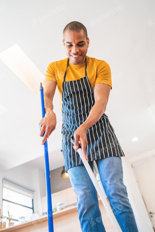 Preview: Portrait Of Young Latin Man Sweeping Wooden Floor With Broom At Home. Cleaning, Housework And