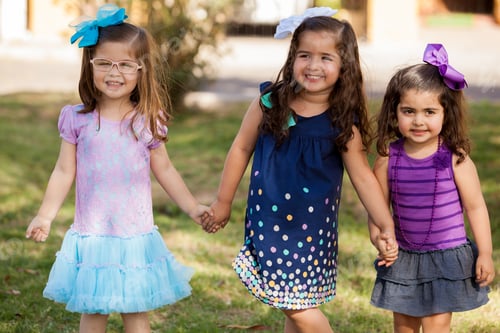 Preview: Beautiful Little Girlfriends Holding Hands And Smiling While Playing In A Park