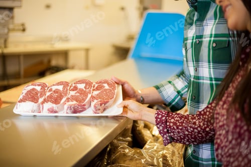 Preview: Closeup Of A Couple Of Young Adults Looking At Some Meat Cuts At The Supermarket
