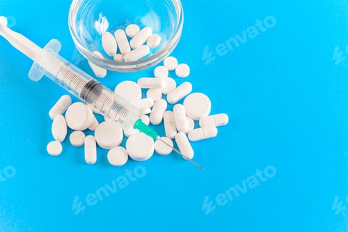 Preview: Close Up View Of Needle With Drug Pills. Light Blue Background. Drug Addiction Concept.