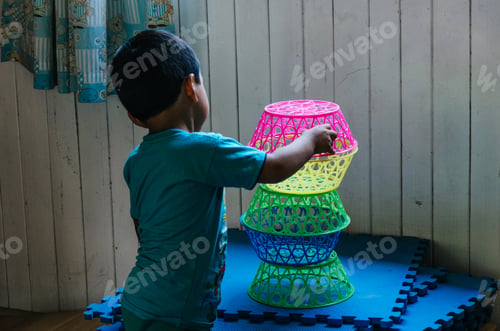 Preview: Boy Playing To Form A Tower With Plastic Baskets