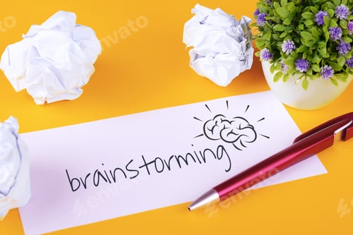 Preview: Paper With "Brainstorming" Text And Crumpled Paper Balls On Yellow Background. Brainstorming Concept