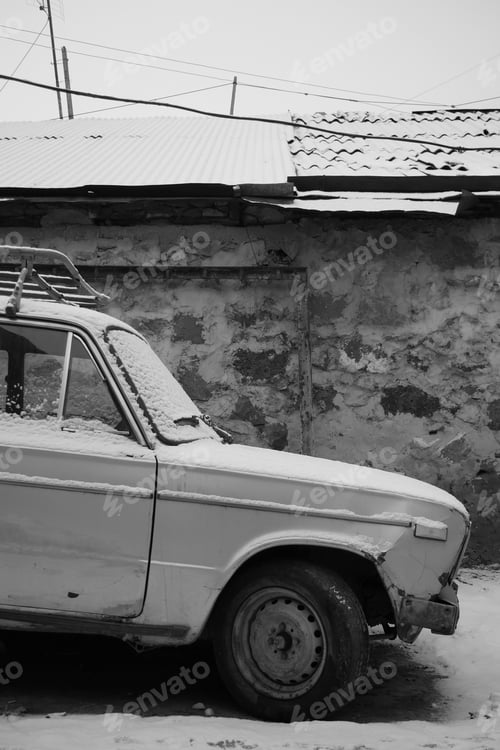 Preview: A Vertical Greyscale Of An Old Car Near An Aged Building Covered In The Snow In Yerevan
