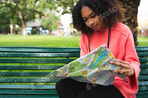 Preview: Portrait Of Young Beautiful Afro American Woman Sitting On Bench In The Park And Looking At A Map