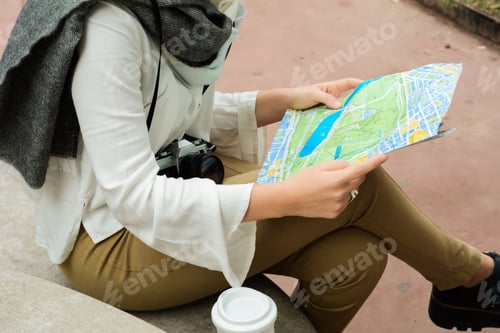 Preview: Young Thoughtful Tourist Girl In Warm Clothes With Map In Her Hands. Outdoors. Travel Concept