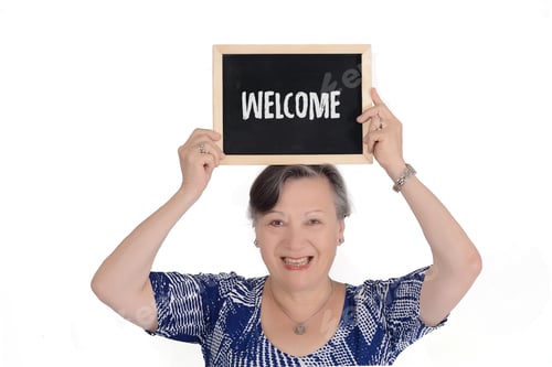 Preview: Elderly Woman Holding Chalkboard With Text "Welcome" In Her Hands. Isolated White Background