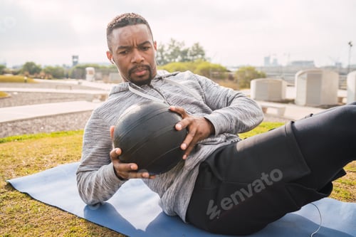 Preview: Portrait Of An Athletic Man Doing Abdominal Exercise With Medicine Ball In The Park Outdoors. Sport