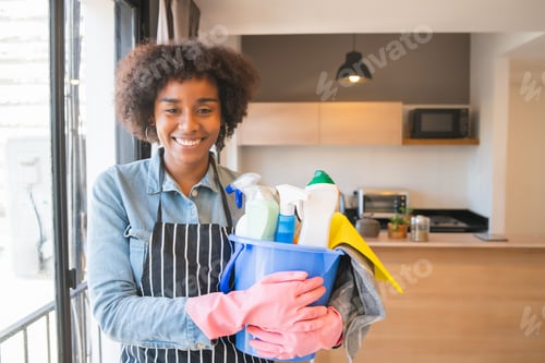 Preview: Portrait Of Young Afro Woman Holding A Bucket With Cleaning Items At Home. Housekeeping And