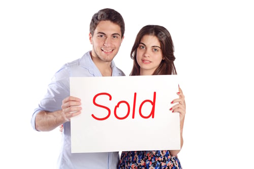 Preview: Portrait Of A Young Beautiful Couple Holding Cardboard With "Sold". Isolated White Background.