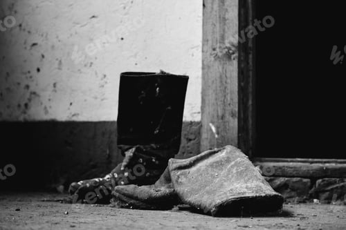 Preview: A Greyscale Closeup Of Old Boots On The Ground Near An Abandoned Building - Cool For Backgrounds