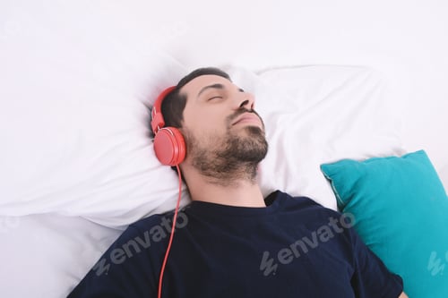 Preview: Attractive Young Man Listening To Music And Relaxed In Bed. Indoors.