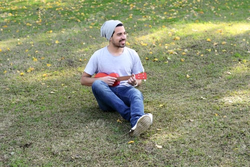Preview: Portrait Of Young Handsome Man Playing The Ukelele In A Park. Outdoors.