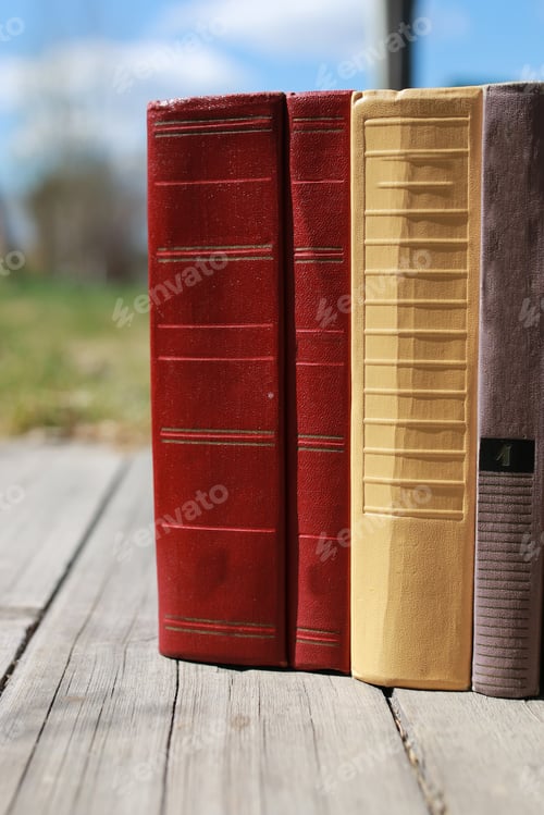 Preview: Books Standing Different Objects On A Wooden Table On A Background Of Blurred Summer Foliage