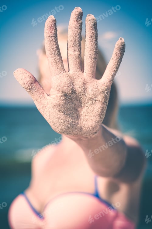 Preview: Woman Show'S Hand Covered With Sand On A Blue Sea Background. Instagram Stylization.