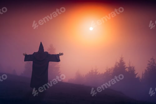 Preview: Fairy Wizard In A Black Cassock Standing On A Hill And Welcome Raising Sun Above The Foggy Valley.