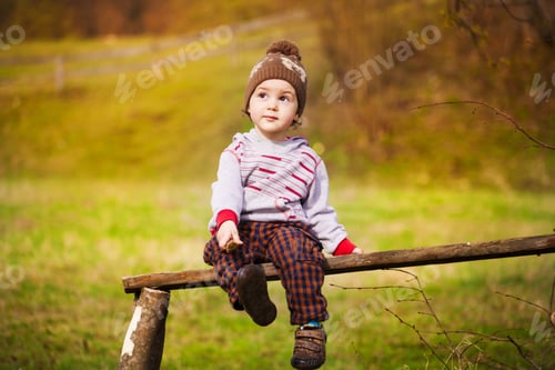 Preview: A Little Boy Is Sitting On A Park Bench Under A Tree.