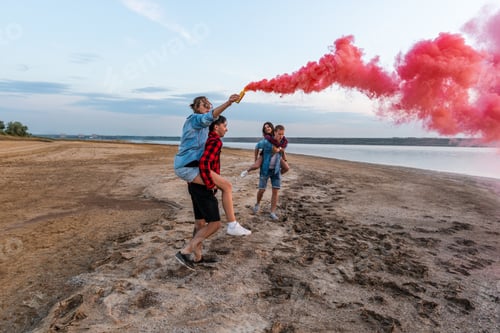 Preview: Group Of Young Friends Running Along The Beach And Holding Hand Flare Or Fusee. Freedom And