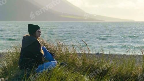 Preview: Pretty Girl Looks Over The Ocean While Sitting In Reed Grass