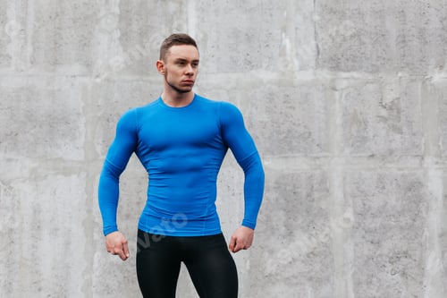 Preview: Portrait Of A Sporty Young Man In A Blue T-Shirt In Gray Wall Background