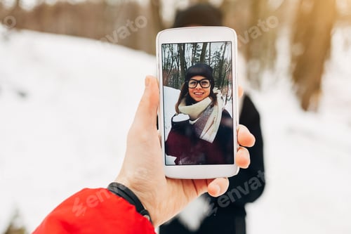 Preview: Man Takes A Picture Of The Girl In Black Coat And Hat With Coffee Cup On The Smartphone In The