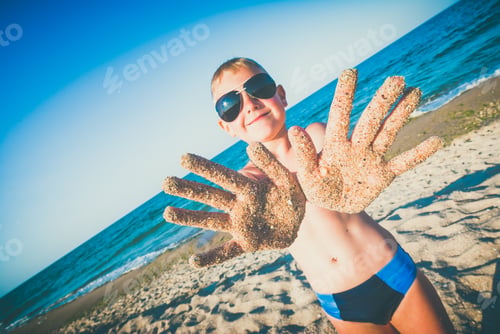 Preview: Happy Small Boy In A Sunglasses With Arms In Sand On A Beach. Instagram Stylization.