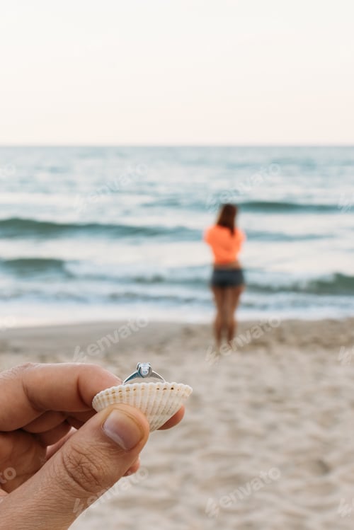 Preview: A Young Man Holding A Ring For A Proposal On The Background Of The Woman He Loved On The Beach