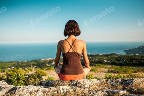 Preview: A Girl Is Sitting On Top Of A Mountain At Sunset. A Woman Is Engaged In Yoga And Sits In A Lotus