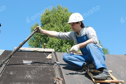 Preview: A Man In The Form Of A Builder Repairs A House