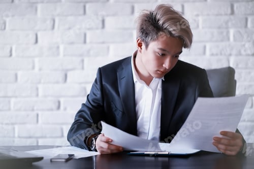 Preview: Young Professional Reading Documents in Bright Office