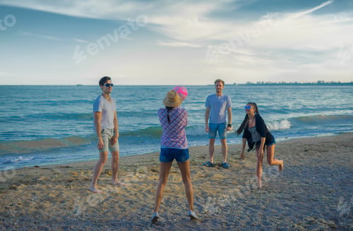 Preview: A Group Of Young And Cheerful Friends Playing Volleyball On A Wild Beach During Sunset.