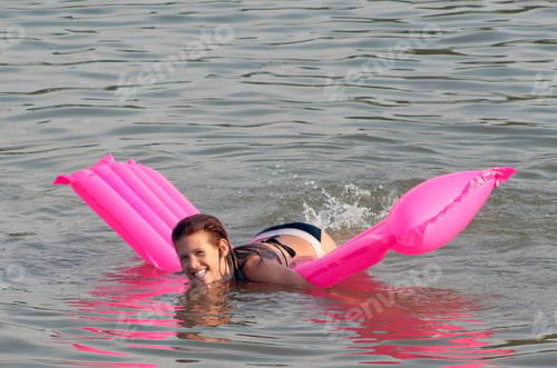 Preview: Cute Teenage Girl Lying On The Pink Mattress That Floats On The Sea Surface.